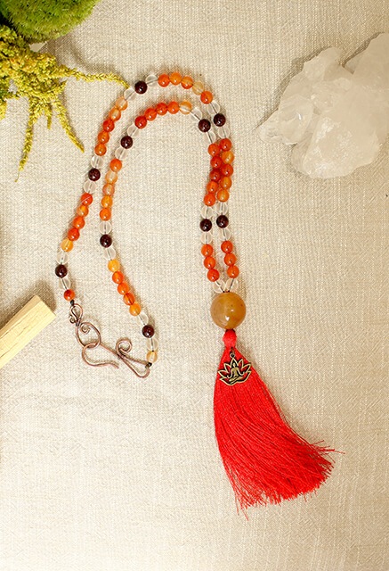 Collier composé de perles de cornaline, cristal de roche, grenat posé sur une table pour illustrer la collection collier de l'accueil de spiritual light