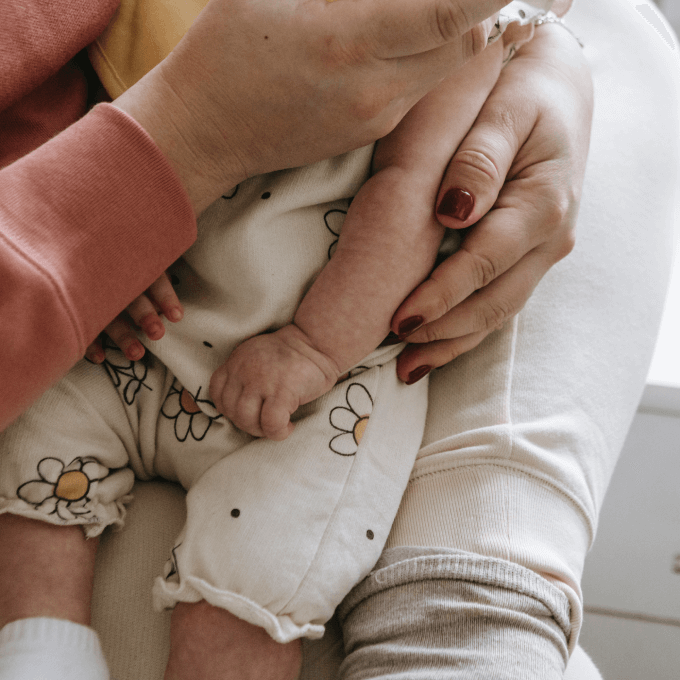 Bébé habillé caliné dans des bras illustrant les pierres de lithothérapie propices pour le post-partum et l'accueil de spiritual light