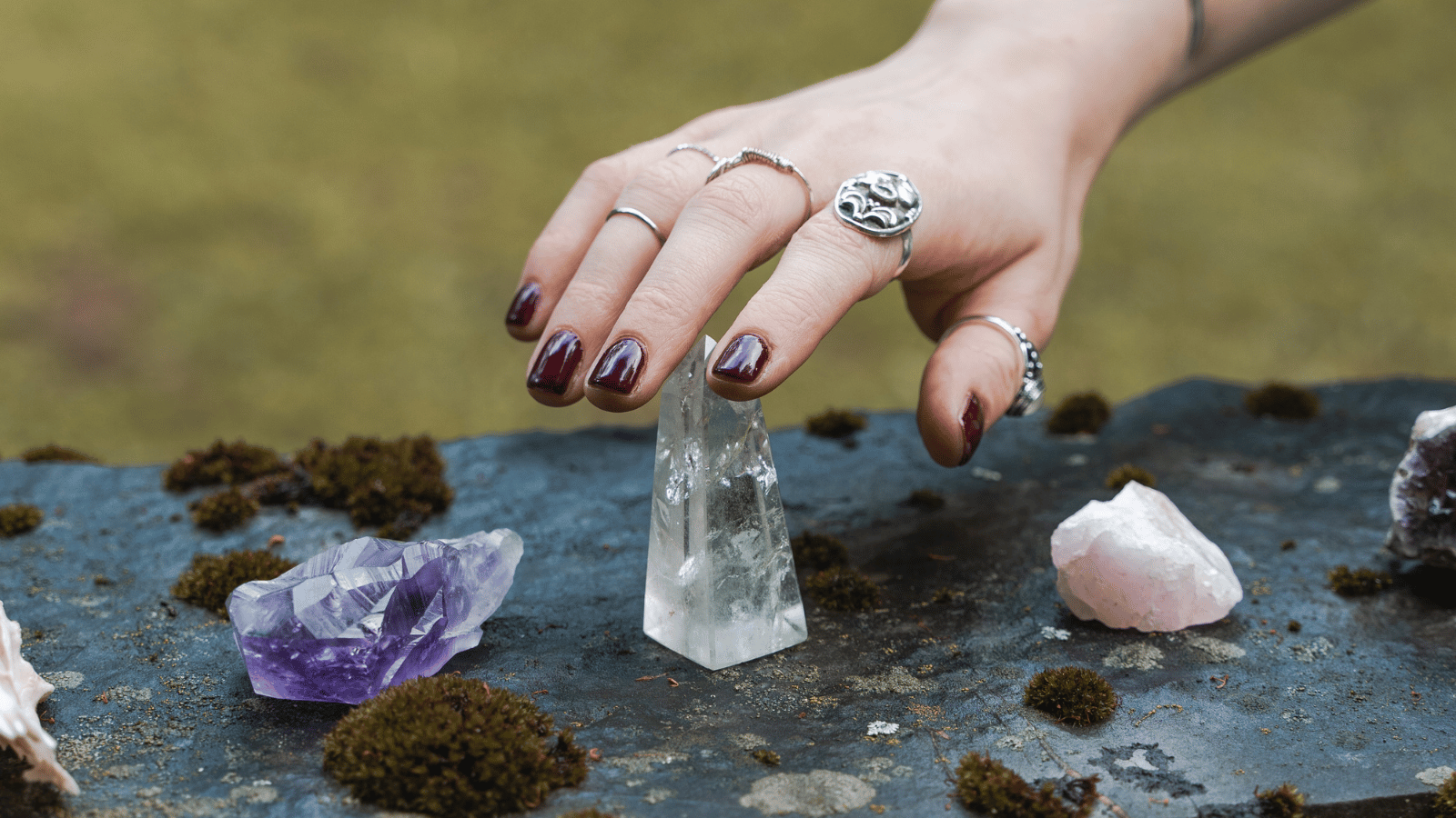 Une main se tenant au dessus de cristaux de quartz sur un sol sombre